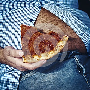 Man with a beer belly eating pizza photo