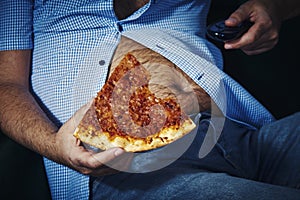 Man with a beer belly eating pizza photo