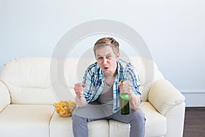 Man with beer and chips watching TV at home