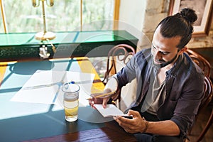 Man with beer writing to notebook at bar or pub