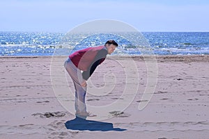 Man beginner is exercising his legs after jogging on the sea sand beach.