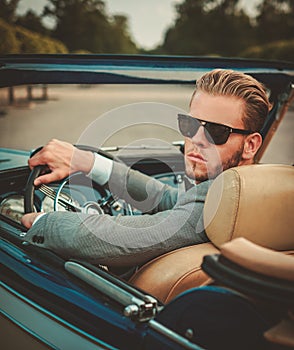 Man behind classic convertible steering wheel