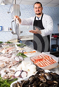 Man behind counter holding fish