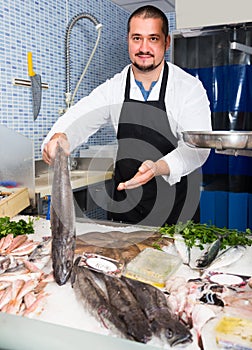 Man behind counter holding fish