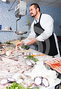 Man behind counter holding fish