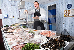 Man behind counter holding fish