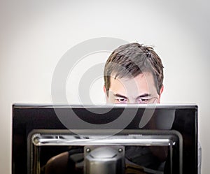 Man behind the monitor of a desk computer