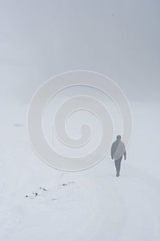 A man from behind walking in snow