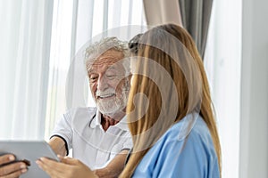 Man being cared for by a private Asian nurse at home suffering from Alzheimer's disease closely care for elderly patients