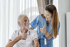 Man being cared for by a private Asian nurse at home suffering from Alzheimer's disease closely care for elderly patients