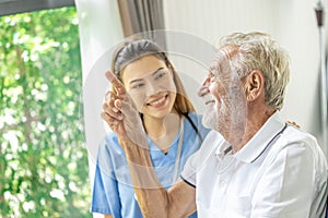 Man being cared for by a private Asian nurse at home suffering from Alzheimer's disease closely care for elderly patients