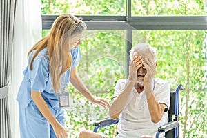 Man being cared for by a private Asian nurse at home suffering from Alzheimer's disease closely care for elderly patients