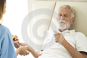Man being cared for by a private Asian nurse at home suffering from Alzheimer's disease closely care for elderly patients