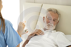 Man being cared for by a private Asian nurse at home suffering from Alzheimer's disease closely care for elderly patients