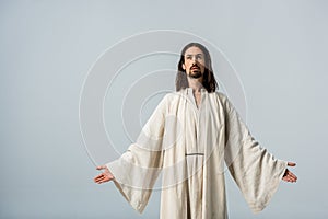 Man with belief standing with outstretched hands isolated on grey