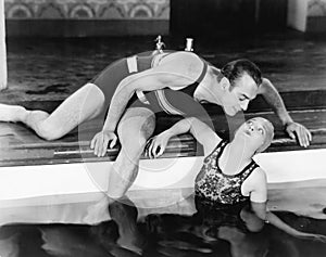 Man bending over to kiss a woman in a swimming pool photo