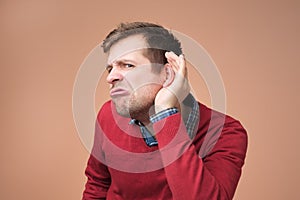 Man bending towards with hand near ear and with curious look and interest listening rumor