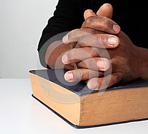 Man with a bible praying with hands clenched together