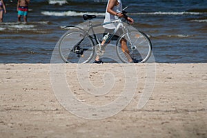 Man with bicycle on beach sand with sea in background