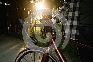 A man with a bicycle in the forest at sunset, close-up.