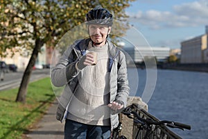 Man in a bicycle helmet drinking coffee from a paper cup