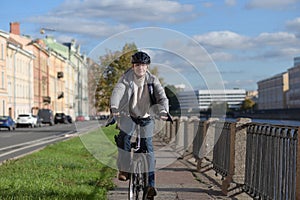 Man in a bicycle helmet on his bike riding along a canal in a city
