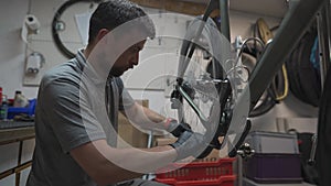 Man bicycle mechanic installs cycle chain on bike. Technician fixes bicycle chain gear at bicycle repair shop. Bicycle