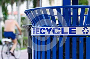 Man on a Bicycle next to a Recycling Bin