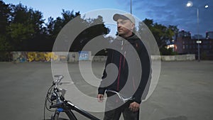 A Man with a Bicycle Among the Night City. Cyclist Illuminated by Night Lanterns. Night Cycling. Positive Guy Looks