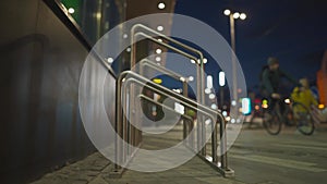 Man in bicycle parking near supermarket at night. Male use bicycle stand near shopping center in city. Cycling