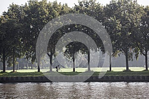 man on bicycle rides along amsterdam rijn kanaal in the netherlands