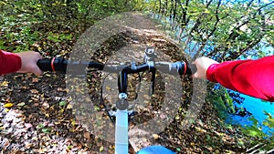 A man on a bicycle rides in forest in the autumn in sunny weather.