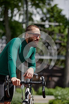 Man on bicycle rides through summer park on sunny day.