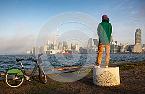 Man with bicycle watching sunset over lake Ontario Waterfront and Toronto downtown panorama