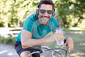 man on bicycle wearing headphones and holding bottle water