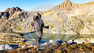 Man with big backpack hiking with a scenic view on the mountains of Hohe Tauern Alps in Carinthia, Austria, Europe. A lake and