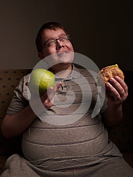 Man with big belly thinking of what to eat - apple or burger. Obesity and gluttony,