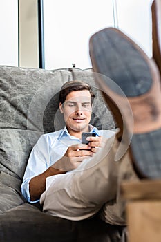 Man in big chair texting with phone