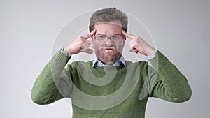 Man in big glasses holds fingers on temples, trying to remember or generate idea.