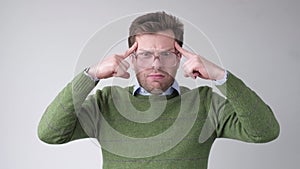 Man in big glasses holds fingers on temples, trying to remember or generate idea.