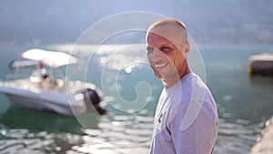 Man with a big smile by the ocean and boat. Happy, smiling, vacation, holiday, freedom concept.