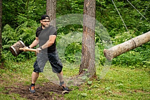 Man with a big wooden hammer training in forest