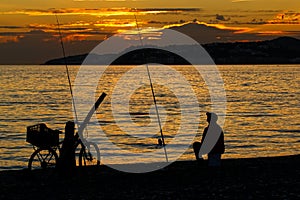 Man, fishing on the coast at sunset. Silhouette. photo