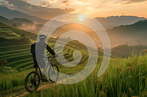 man on bike on path in a mountainous landscape with rice terraces at sunset