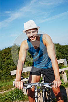 Man, bike ride and portrait in nature for travel outdoor and relax for break in afternoon. Young person, smile and