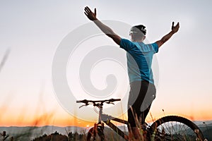 Man biker greats a sunset in mountains