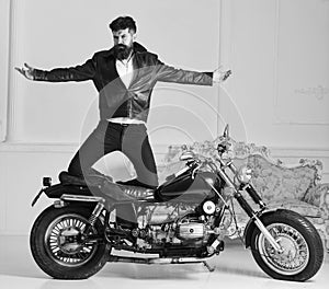 Man biker in leather jacket near motor bike in luxury living room interior background. Hipster biker brutal in leather