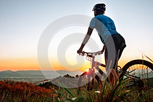 Man biker man meets a sunset in top of hill over the city