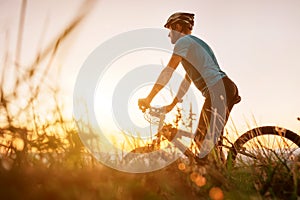 Man biker man meets a sunset in top of hill over the city. Active sport people concept image