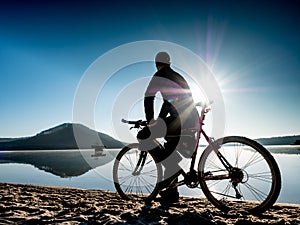 Man biker sit on bike frame and watch the calm lake